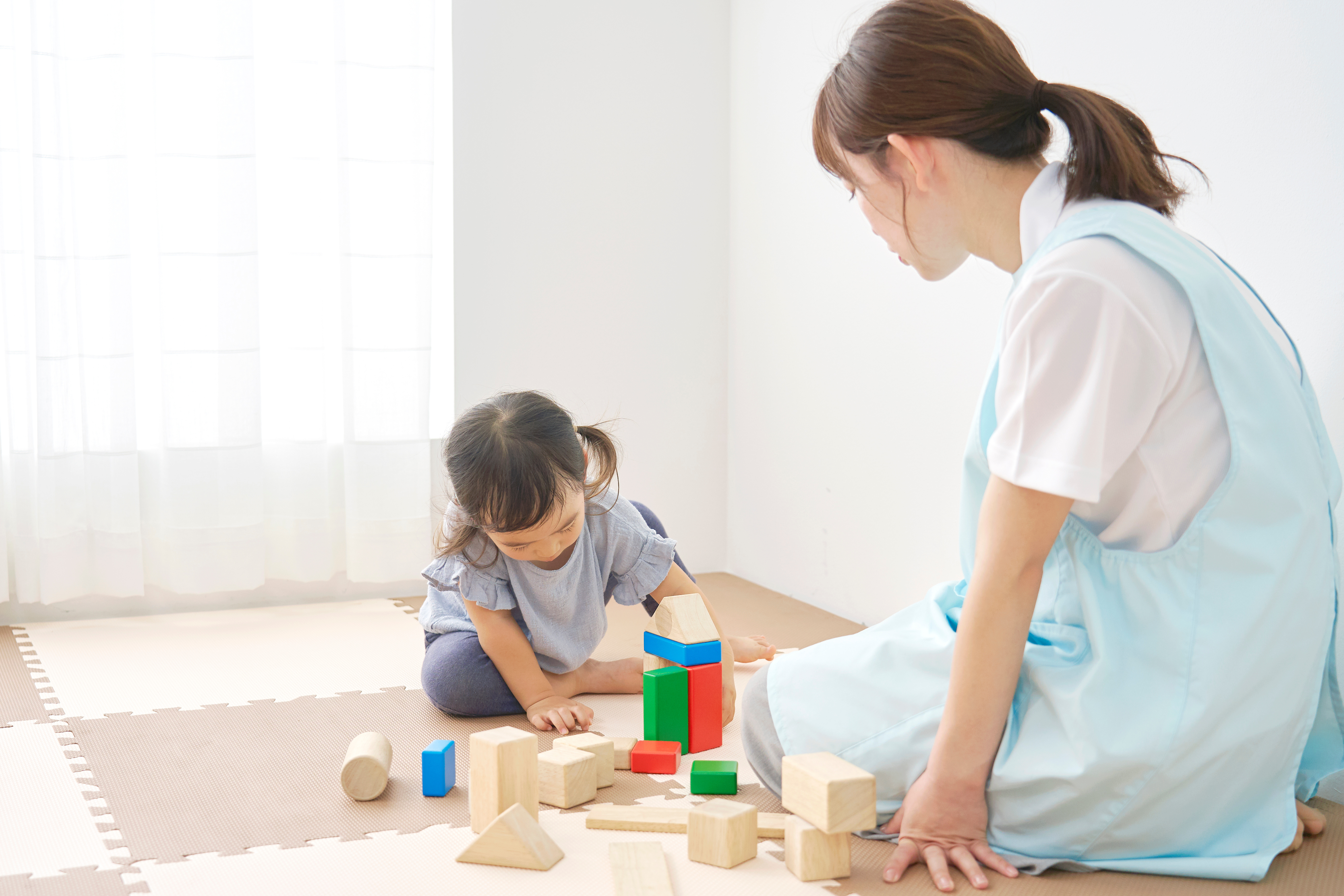 園内で積み木で遊ぶ子どもと保育士